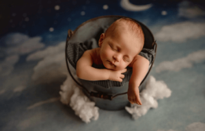 newborn baby in a bucket with a green background