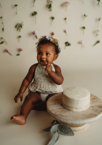 african american baby sitting next to a cake