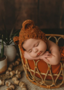 a baby sleeping in a basket with a cute hat